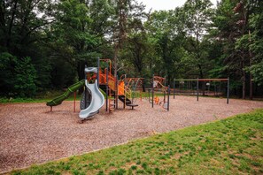 A playground with a slide and climbing structures. - Cozy Lakefront Retreat | Sauna, Hot Tub & Ski (Wild Rose)