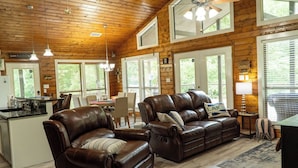 A spacious living room with leather sofas, a dining area, and a kitchen.