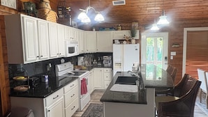 A kitchen with wooden ceiling, white cabinets, a central island, and pendant lighting.