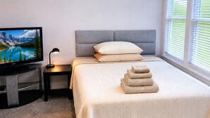 Een hotelkamer met een bed, een televisie, een lamp en een raam met jaloezieën.