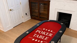 Een pokertafel in een kamer met een open haard, een televisie en een raam.