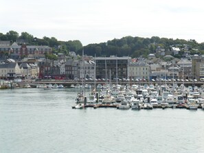 A marina with numerous boats docked, surrounded by buildings and a hilly backdrop. - Quiet Designer Apartment in Fecamp (Fecamp)