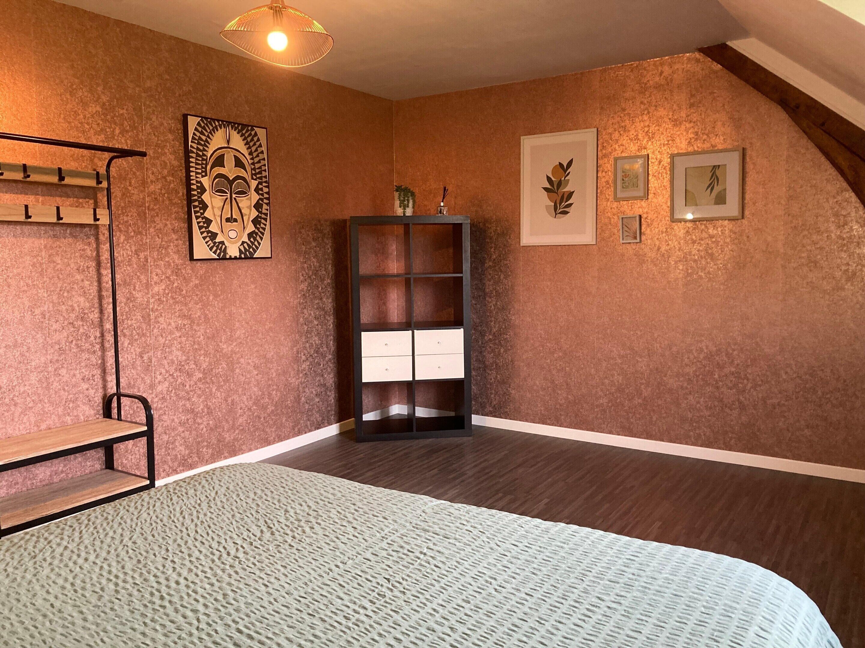 A bedroom with a bunk bed, a wooden bench, a bookshelf, and framed artwork on the walls.