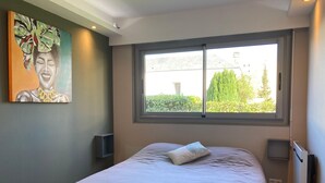 Un dormitorio con cama, ventana, un cuadro y un radiador.