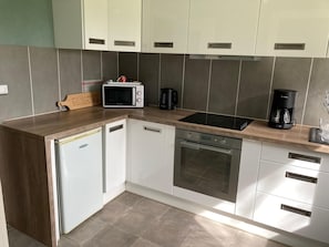 A compact kitchen with a microwave, coffee maker, and built-in oven. - Quiet Designer Apartment in Fecamp (Fecamp)