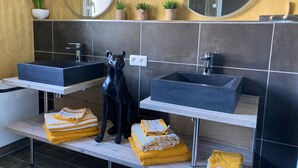 Un baño moderno con dos lavamanos, un espejo y una estatua decorativa de un panterón negro.