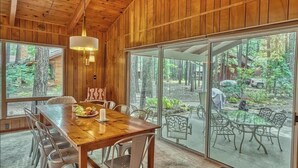 A wooden interior with a dining table and chairs, a large window, and a view of the outdoors. - Pinetop Sinatra Getaway (Pinetop Country Club)