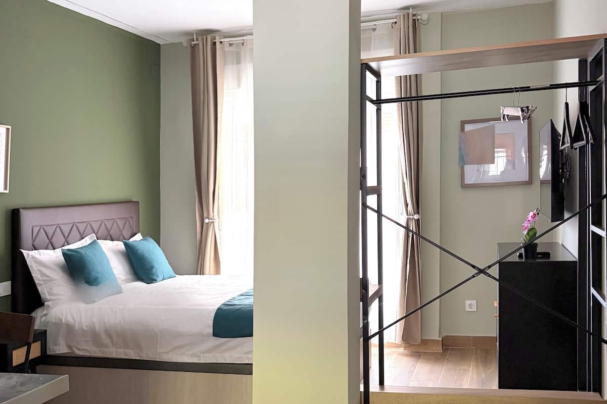 A bedroom with a bed, a desk, and a view of a staircase.