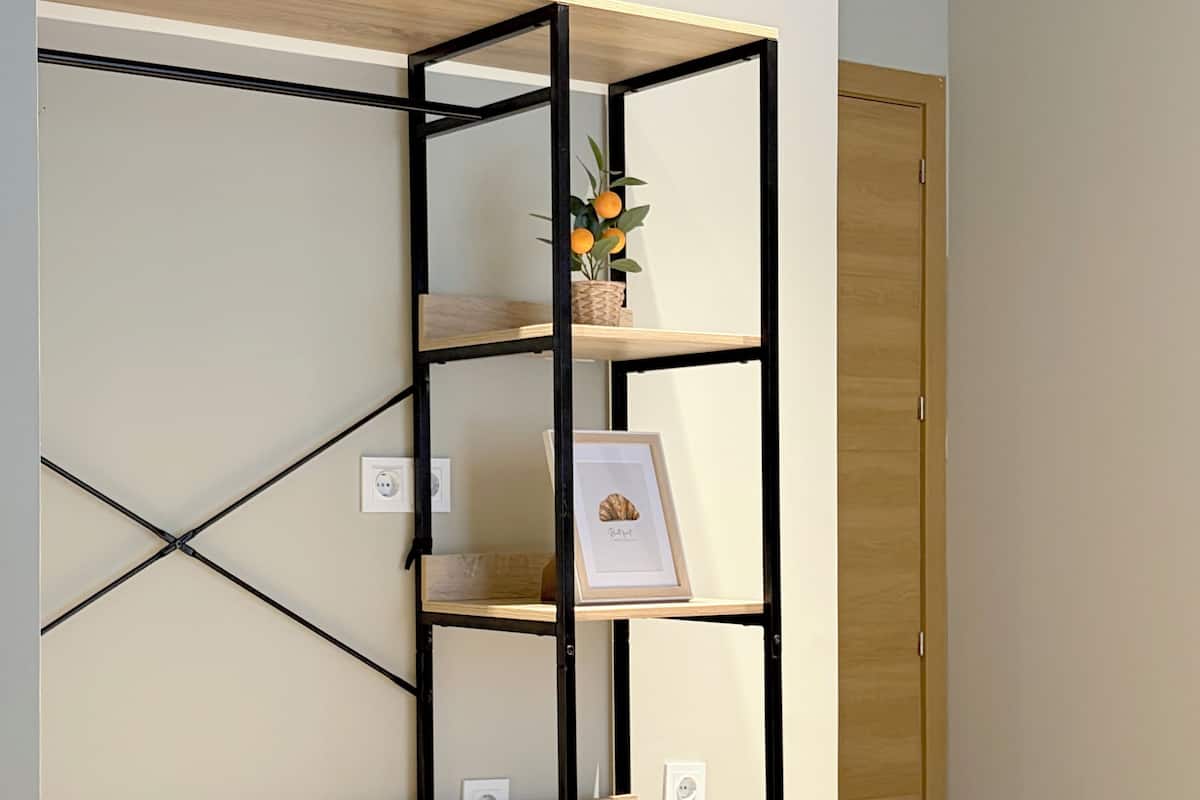 A room with a bed, a wall-mounted shelf unit, and a door.