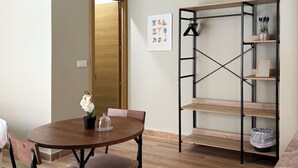 Ein Essbereich mit Holztisch und -stühlen, einem Bücherregal und einer Tür, die in einen anderen Raum führt.