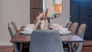 A dining area with a wooden table, grey upholstered chairs, and a decorative plant. - Modern Oasis with Heated Private Pool in Anaheim (Anaheim)