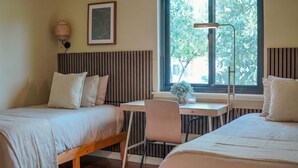 A bedroom with two beds, a desk, a chair, a floor lamp, and a window with a view of trees. - Modern Oasis with Heated Private Pool in Anaheim (Anaheim)