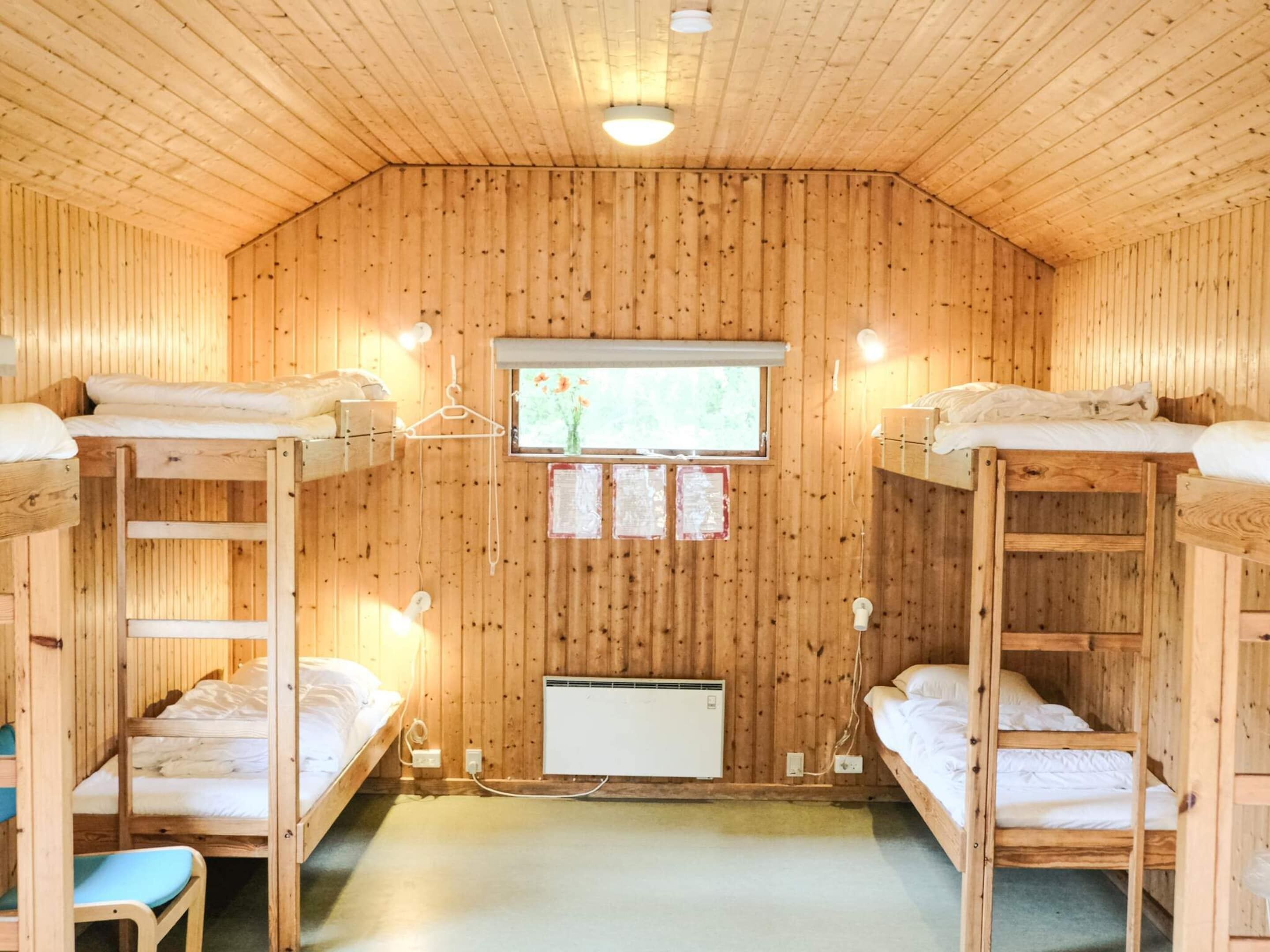 A wooden cabin with bunk beds, a window with a view, and a heater.