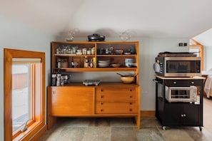 Eine kleine Küche mit einem Holzkorpus, einer Mikrowelle und einem Backofen.