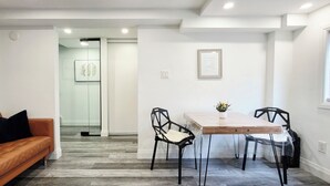 A modern interior with a wooden dining table, black chairs, a leather sofa, and a framed picture on the wall.