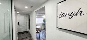 Un couloir avec une porte, un panneau encadré portant le mot «
rire
», et un coin repas avec une table et des chaises.