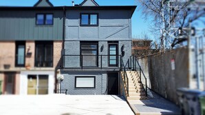 A modern two-story house with a stone facade, a visible garage door, and a staircase leading to the entrance.