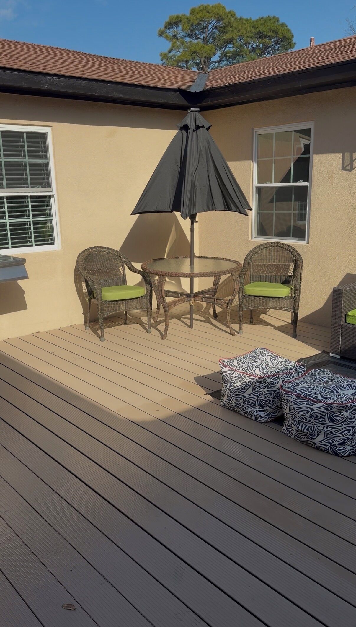 A patio with wicker furniture, a round table, and a black umbrella.