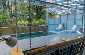 Área externa coberta com piscina, cadeiras de descanso e balanço.