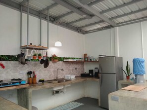 Uma cozinha compacta com fogão a gás embutido, pia, geladeira e diversos utensílios e eletrodomésticos de cozinha.