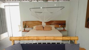 Un lit avec une tête de lit en bois, un baldaquin et deux tables de chevet avec des lampes.