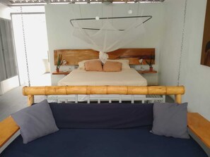 Uma cama com cabeceira de madeira, um dossel e duas mesas de cabeceira com abajures.