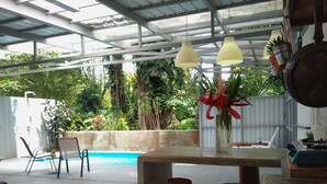 An outdoor patio with a pool, a table with a vase of flowers, and hanging pendant lights. - Beautiful 1-bedroom with Private Pool in Playa Negra Puerto Viejo (Playa Negra, Puerto Viejo de Talamanca)