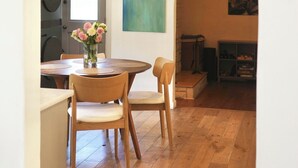 Un interior con zona de comedor, suelo de madera, lámpara colgante y un cuadro en la pared.