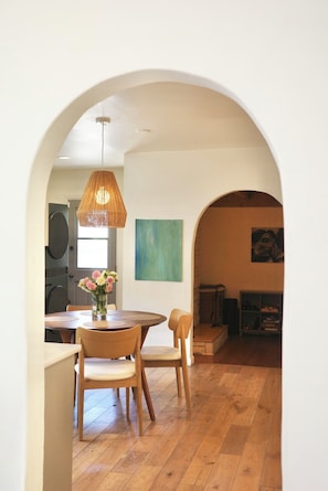 An interior with a dining area, wooden flooring, a hanging light fixture, and a painting on the wall. - Spanish Oasis in Miracle Mile w/ Backyard (Los Angeles)