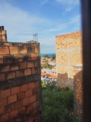 A brick wall with a metal structure on top, a partially constructed building, and a view of a town with buildings and greenery.