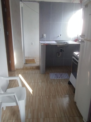 Una cocina compacta con un lavamanos, estufa y un refrigerador pequeño.