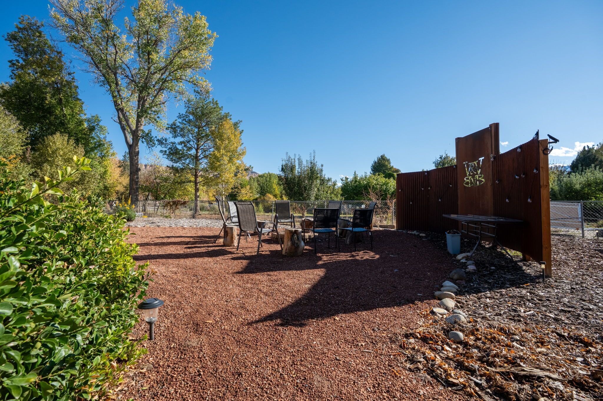 A patio area with outdoor furniture, a wooden fence, and a gravel ground.