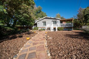 A two-story house with a porch, a stone pathway, and a garden with mulch and plants. - Charming 4-bedroom house in Fruit and Wine country  Palisade! Retired BnB (Palisade)
