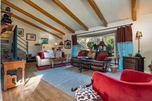 A cozy living room with a staircase, a leather sofa, a red armchair, and a wooden coffee table. - Charming 4-bedroom house in Fruit and Wine country  Palisade! Retired BnB (Palisade)
