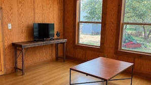 A room with wooden walls, a wooden floor, a TV on a desk, and a ping pong table. - The Farmhouse at the Starlight PK Ranch and Venue on Possum Kingdom Lake (Graham)