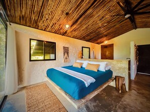 Ein Schlafzimmer mit Bett, Fenster, Wandleuchte und Deckenventilator.