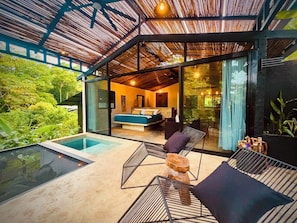 Ein moderner Außenbereich mit einem Schlafzimmer mit Glasfassade, einem Pool und Liegestühlen.