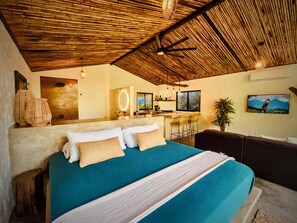 A bedroom with a large bed, a small sitting area, a kitchen area, and a dining area. - Pond House l Waterfront Jungle Retreat w/Private Pool, Fire Pits, Hammocks & AC (Provincia de Puntarenas)