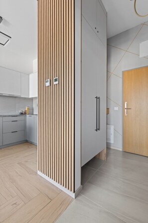 Eine moderne Küche mit grauen Schränken, einer Holzvertäfelung und einer Holztür.