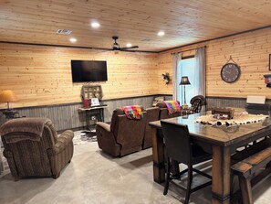 Ein Zimmer mit Holzvertäfelung, einem Fernseher, einem Tisch mit Stühlen und einem Kamin.