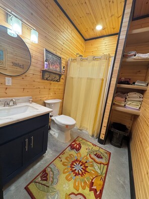 A wooden-paneled bathroom with a sink, toilet, and shower curtain. - SIMPLY BLESSED ON LANAN BAY (Many)