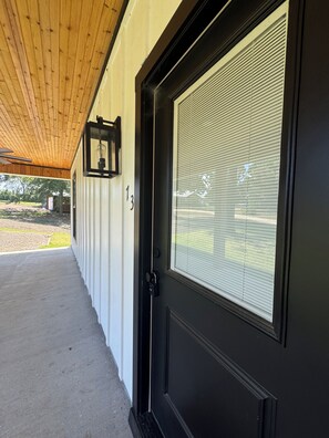 Eine schwarze Tür mit Fenster, die Zahl 13 an der Wand und eine Holzdecke.