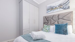 Une chambre à coucher avec un lit, une armoire, une tête de lit et un tableau accroché au mur.