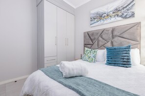 Ein Schlafzimmer mit Bett, Kleiderschrank, Kopfteil und einem Bild an der Wand.