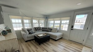 Un salón con un sofá modular, una mesa de centro y ventanas amplias.