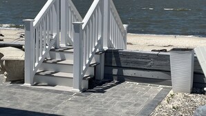 Una escalera de madera blanca que lleva a una zona de playa con vistas al océano.