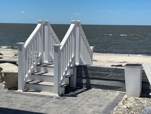 A white wooden staircase leading to a beach area with a view of the ocean. - This spectacular home marries BEACHfront and BAYfront! (Cape May Court house)