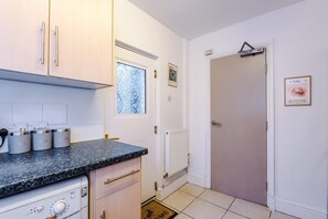 Eine Küche mit Granitarbeitsplatte, weißen Schränken, einem Einbauofen und einem Fenster mit dekorativem Muster.