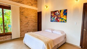 Une chambre avec un lit, un mur en briques, un plafond en bois et une grande fenêtre.
