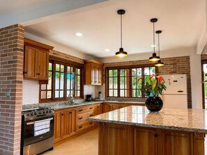 A kitchen with wooden cabinets, a granite countertop, a stainless steel oven, and a refrigerator. - Villa Diana Calima, country house (Calima)
